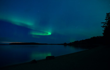 Naklejka na ściany i meble Northern lights dancing over calm lake in Farnebofjarden national park in Sweden.