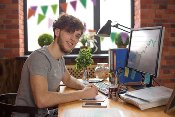 Young smiling man working at his workplace