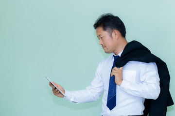A studio image of an Asian businessman with a handsome beard and hold the tablet a mint green background