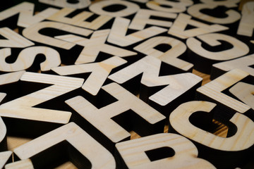 Random wooden block letters lying on wooden surface.