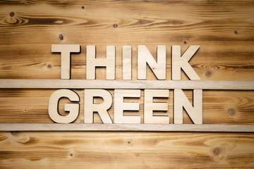 THINK GREEN words made of wooden block letters on wooden board, top view.