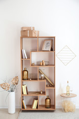 Wooden shelving unit with golden decor near white wall