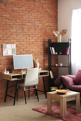 Interior of stylish room with wooden table and workplace near brick wall