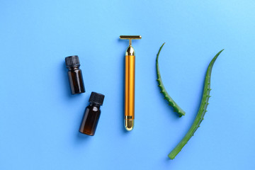Facial massage tool with essential oil and aloe vera on color background
