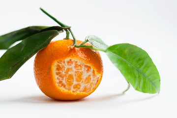 The mandarin partly without peel with green leafs on white background free space for text isolate