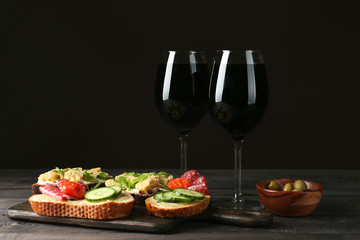 Glasses of red wine with tasty bruschettas on table