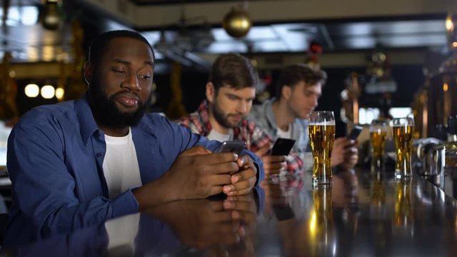 Lonely men sitting in pub, looking through dating sites in cellphones, addiction