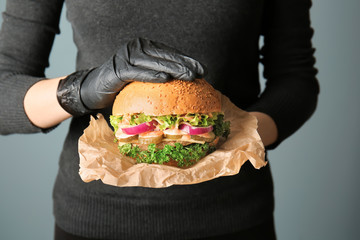 Woman with tasty burger on grey background