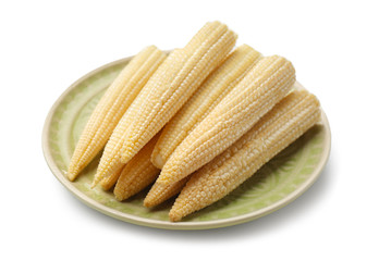 Plate with baby corn cobs on white background
