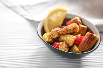 Bowl with tasty corn cobs, chili and lemon on white table