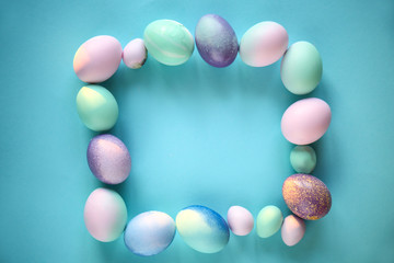 Frame made of Easter eggs on color background