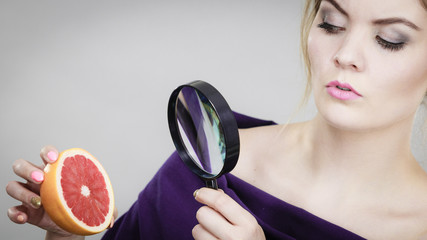 Woman holding magniferlooking grapefruit