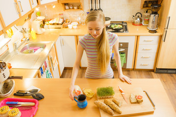 Woman in kitchen holding knife making healthy sandwich