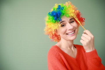 Funny woman with wig for April Fools' Day celebration on color background