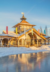Elegant wooden teremok house decorated with woodcarving on bank of  frozen lake