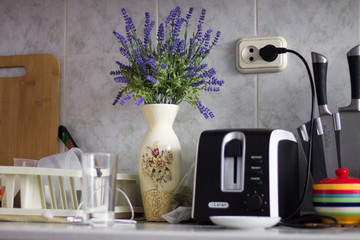 A beautiful bunch of lavender is standing on the kitchen table next to the toaster and the dishes, image is suitable for an interior designer