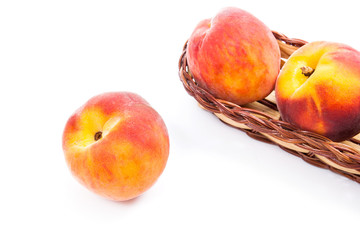 Single ripe peach fruit and several in basket isolated on white background.