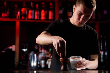 Barman fills black burnt ceramic bowl for hookah smoking different types of tobacco.