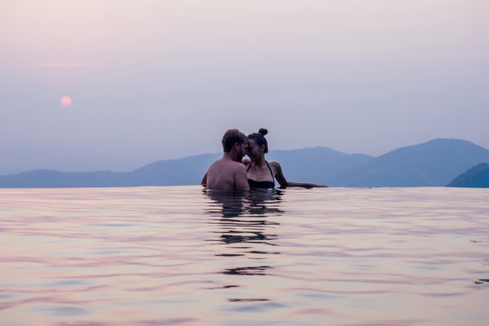 happy couple in the pool looking at mountain landscape in India Goa Kerala wildernest luxury resort . Man and woman together enjoying beautiful mountains on summer travel - Powered by Adobe