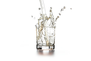 Whiskey pouring into glass with ice on light background..