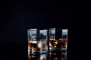 Two glasses of whiskey with ice isolated on black background..