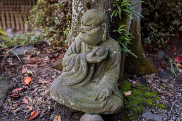 Old statue of a seated Buddhist monk made of stone close-up