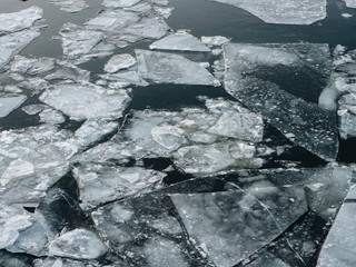 Ice on the river at winter time in december with a dark water and white shutterd ice on it