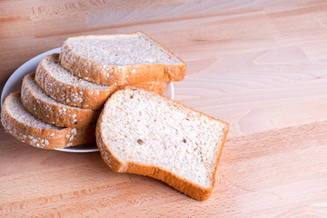 Slice whole wheat bread on wooden floor background.