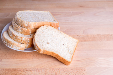 Slice whole wheat bread on wooden floor background.