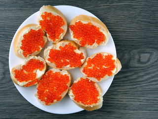 Red caviar on sandwiches on a wooden table