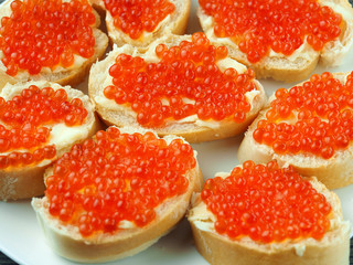Red caviar on sandwiches on a wooden table
