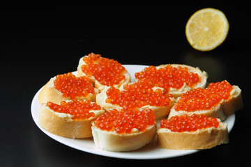 Red caviar on sandwiches in a plate on a dark background