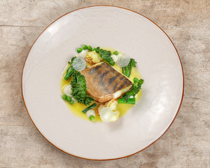 Overhead shot of pikeperch on a white plate with ligth garnish