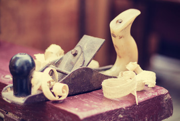 Joinery – old wooden plane and chips in a workshop of the carpenter, retro concept.