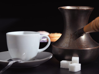 Old Cezve and white coffee cup on a dark background.