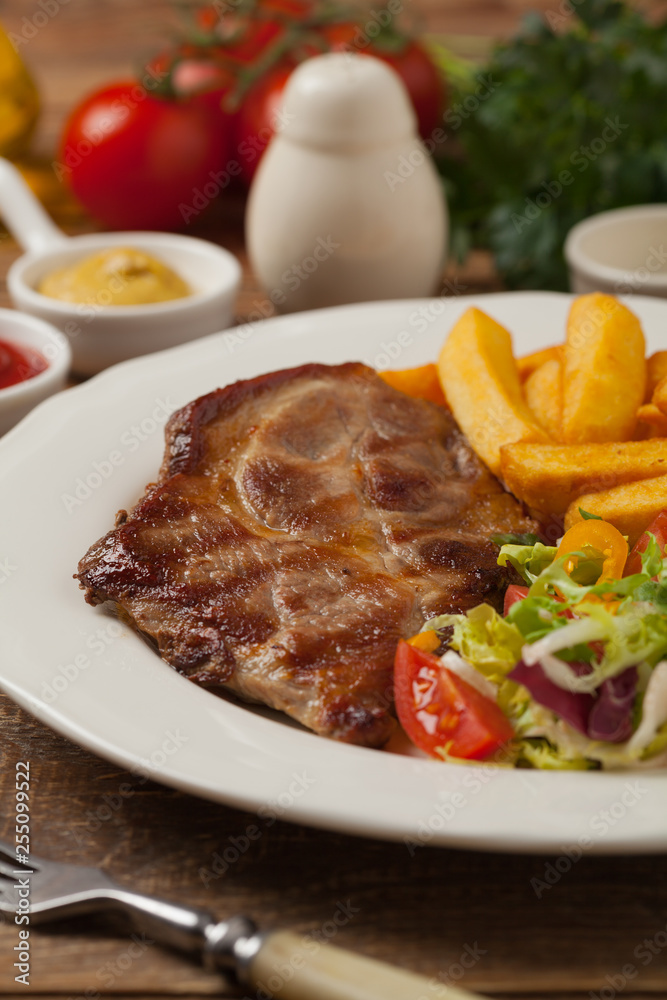 Wall mural grilled pork neck served with french fries and salad.