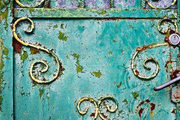 Rusty metal door with green paint gray handle and yellow curls and rust corrosion, destruction, changes, metal corrosion, naming, exfoliation.