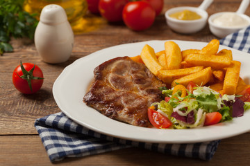 Grilled pork neck served with French fries and salad.