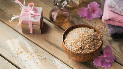 Sea salt, natural handmade soap, natural cosmetic oil and colorful towels with azalea flowers on rustic wooden background