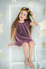 Portrait of a beautiful blue-eyed girl, little sitting on a chair. Spring break, Mother's Day, Women's Day.