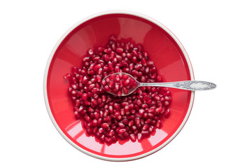 Pomegranate seeds on a red plate with a spoon on a white background 