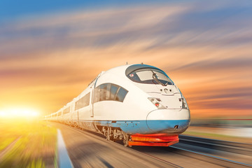 Locomotive high speed train runs on rail track, sunset sky.