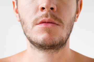 Obraz premium Young adult man with short beard. Isolated on gray background. Men's issues. Face close up. Front view.