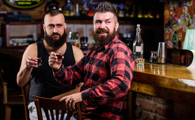 Strong alcohol drinks. Friends relaxing in pub. Friday relax in pub. Cheers concept. Hipster brutal bearded man drinking alcohol with friend at bar counter. Men drunk relaxing at pub having fun
