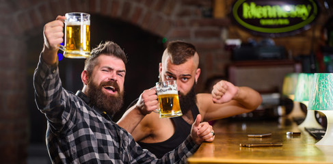 Friends relaxing in pub with beer. Refreshing beer concept. Men drinking beer together. Hipster brutal man drinking beer with friend at bar counter. Men drunk relaxing having fun. Alcohol drinks