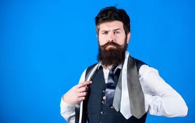 Man bearded hipster hold few neckties on blue background. Guy with beard choosing necktie....