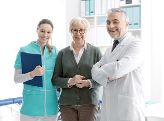 Senior patient posing with medical staff at the clinic