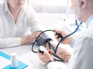 Doctor measuring blood pressure of a senior patient