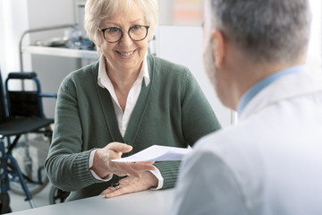 Professional doctor giving a prescription to a senior patient