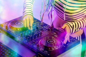 Asian girl DJ is playing a turntable in night party is colorful.